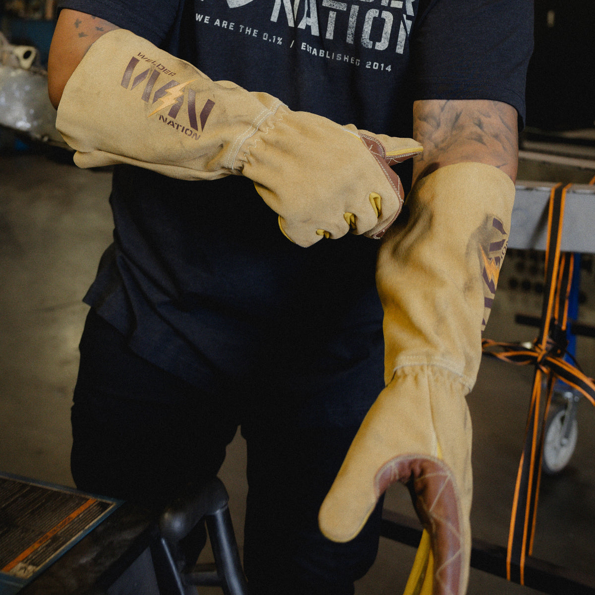 Person wearing tan welder nation premium stick welding gloves in an industrial setting
